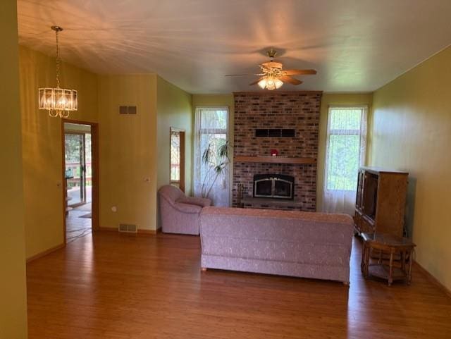3108 Hawks Haven Trl, Deforest, WI 53532 - living room featuring wood finished floors, a chandelier, a brick fireplace, a ceiling fan, and baseboards