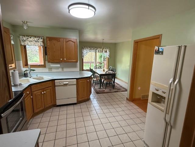 3108 Hawks Haven Trl, Deforest, WI 53532 - kitchen with white appliances, a sink, a chandelier, light tile patterned floors, and brown cabinetry