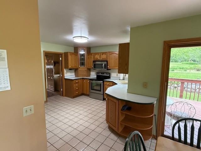 3108 Hawks Haven Trl, Deforest, WI 53532 - kitchen featuring appliances with stainless steel finishes, brown cabinetry, open shelves, light countertops, and light tile patterned floors