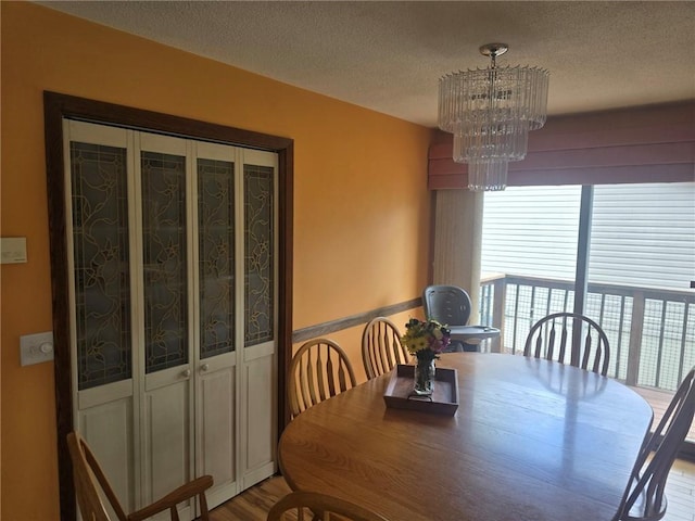 2626 Abbe Hill Dr, Eau Claire, WI 54703 - dining area featuring a chandelier, a textured ceiling, and wood finished floors