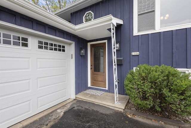 2104 Hazel St, Oshkosh, WI 54901 - property entrance featuring board and batten siding, a garage, and asphalt driveway