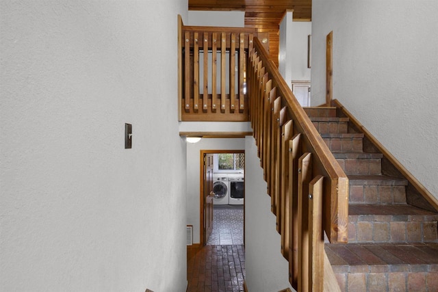 2104 Hazel St, Oshkosh, WI 54901 - staircase with washing machine and clothes dryer, a textured wall, and brick flooring