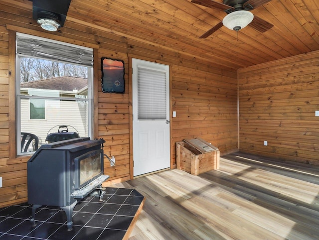 W11065 Menominee Rd, Portage, WI 53901 - living area featuring a wood stove, wooden walls, a ceiling fan, wooden ceiling, and wood finished floors