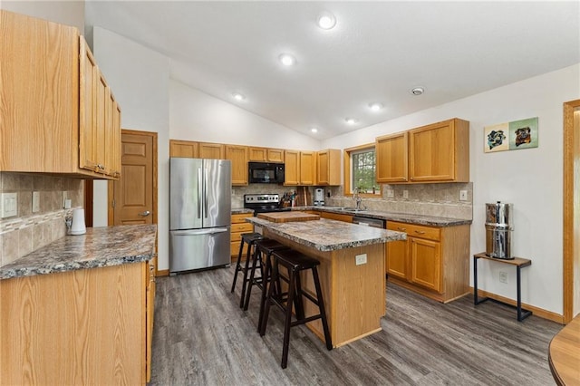 819 Fairway Cir, Black River Falls, WI 54615 - kitchen featuring stainless steel appliances, vaulted ceiling, a breakfast bar area, dark countertops, and backsplash