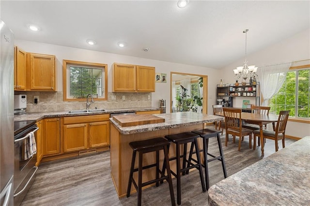 819 Fairway Cir, Black River Falls, WI 54615 - kitchen with a sink, stainless steel electric stove, a chandelier, tasteful backsplash, and lofted ceiling