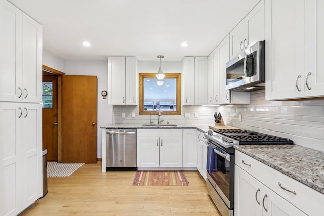 4912 Schofield St, Monona, WI 53716 - kitchen with stainless steel appliances, a sink, light wood-style floors, tasteful backsplash, and white cabinets