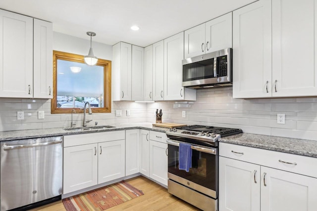 4912 Schofield St, Monona, WI 53716 - kitchen with stainless steel appliances, a sink, white cabinetry, backsplash, and light wood-style floors