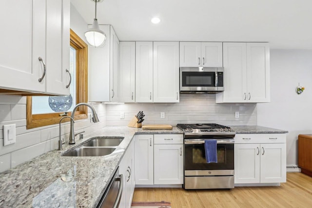 4912 Schofield St, Monona, WI 53716 - kitchen featuring appliances with stainless steel finishes, a sink, white cabinets, light stone countertops, and decorative backsplash