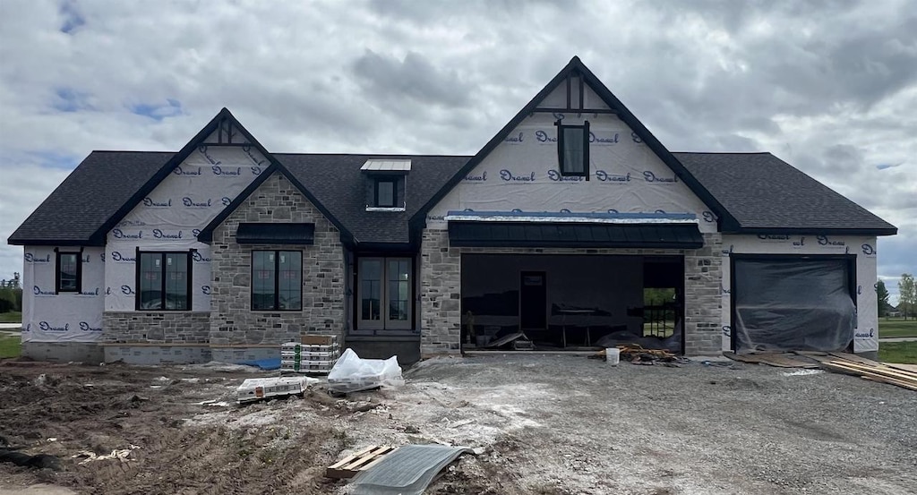 143 Beckerae Ct, Wrightstown, WI 54180 - unfinished property with stone siding, a garage, roof with shingles, and stucco siding