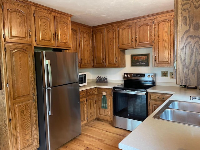 17235 Little Archibald Rd, Townsend, WI 54175 - kitchen featuring stainless steel appliances, a sink, brown cabinetry, and light countertops