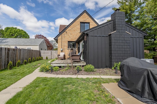4892 N Mohawk Ave, Glendale, WI 53217 - back of property featuring board and batten siding, a wooden deck, brick siding, and a chimney