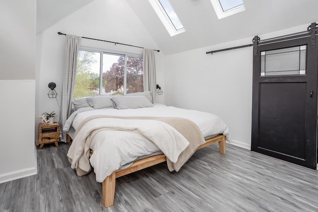 4892 N Mohawk Ave, Glendale, WI 53217 - bedroom with a skylight, a barn door, wood finished floors, baseboards, and high vaulted ceiling