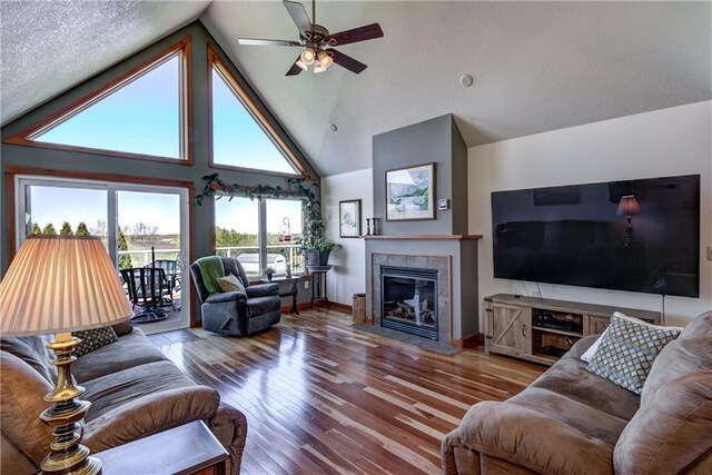 1816 186th St, Chippewa Falls, WI 54729 - living area featuring a ceiling fan, a tiled fireplace, hardwood / wood-style floors, high vaulted ceiling, and baseboards