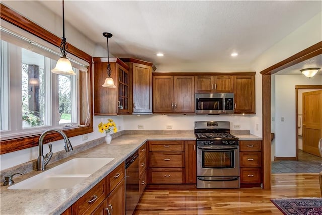 1816 186th St, Chippewa Falls, WI 54729 - kitchen with stainless steel appliances, a sink, decorative light fixtures, glass insert cabinets, and brown cabinetry