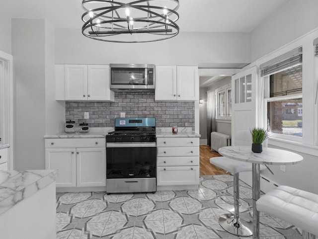 4101 N 14th St, Milwaukee, WI 53209 - kitchen with appliances with stainless steel finishes, radiator heating unit, white cabinets, and a chandelier