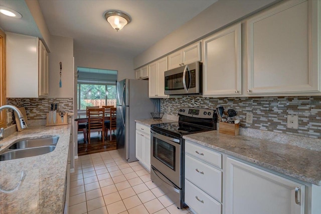 3514 Valley Ridge Rd, Middleton, WI 53562 - kitchen featuring appliances with stainless steel finishes, a sink, light tile patterned floors, tasteful backsplash, and light stone counters