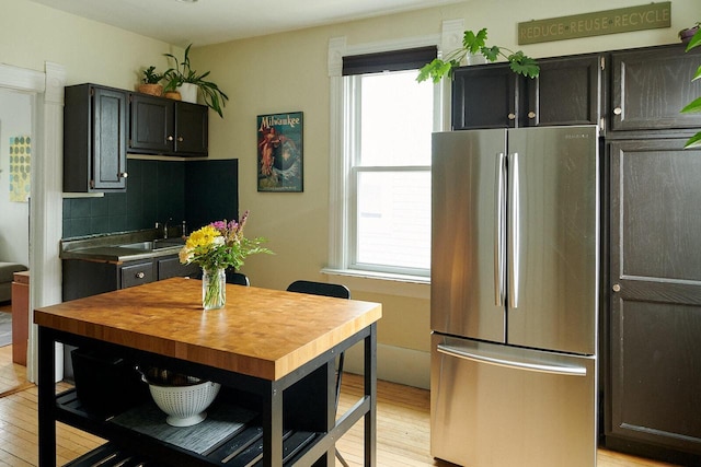 1605 E Webster Pl, Milwaukee, WI 53211 - kitchen with freestanding refrigerator, light wood-style floors, a sink, decorative backsplash, and dark cabinets