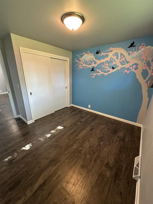 174 Mckinley Ave, Clintonville, WI 54929 - unfurnished bedroom with dark wood-style flooring, baseboards, and a closet