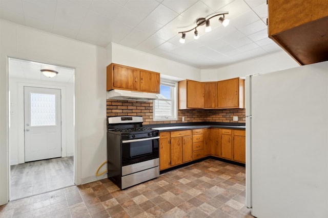 815 Madison St, Little Chute, WI 54140 - kitchen with freestanding refrigerator, gas stove, under cabinet range hood, dark countertops, and tasteful backsplash