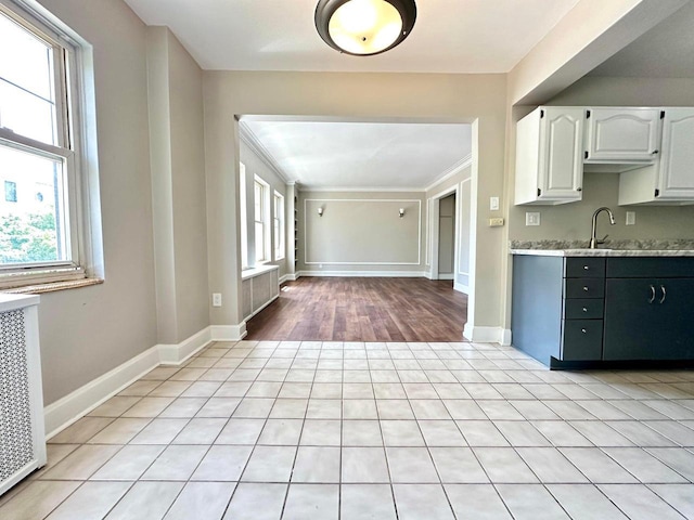 1028 E Juneau Ave Unit 204-206, Milwaukee, WI 53202 - kitchen with healthy amount of natural light, white cabinets, a sink, baseboards, and crown molding