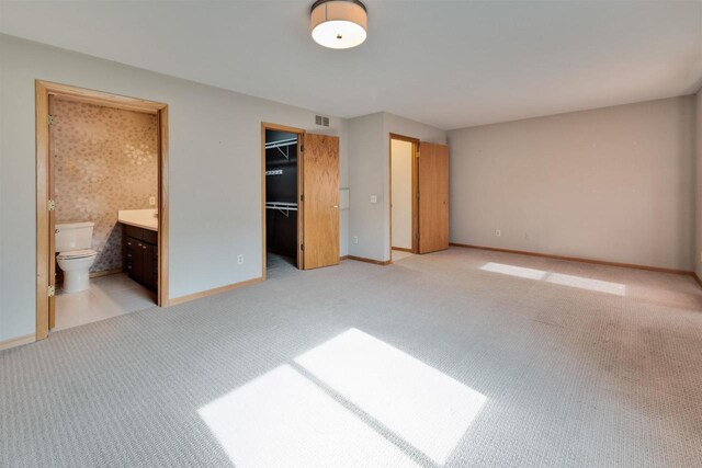 69 Ponwood Cir, Madison, WI 53717 - unfurnished bedroom featuring light colored carpet, baseboards, a walk in closet, ensuite bathroom, and a closet
