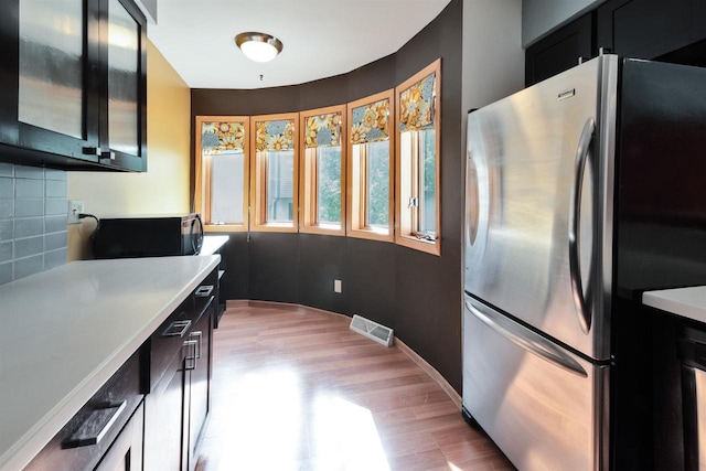 69 Ponwood Cir, Madison, WI 53717 - kitchen featuring freestanding refrigerator, light wood-type flooring, dark cabinets, light countertops, and decorative backsplash