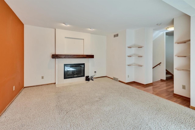 69 Ponwood Cir, Madison, WI 53717 - unfurnished living room with a fireplace with flush hearth, carpet flooring, baseboards, and wood finished floors