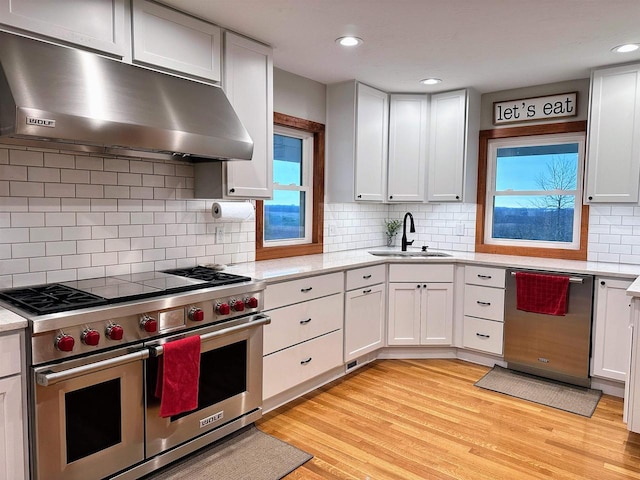 11691 County Road P, Bagley, WI 53801 - kitchen with stainless steel appliances, under cabinet range hood, a sink, light wood-style floors, and decorative backsplash