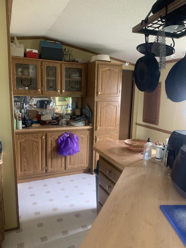 39 Douglas St, Westby, WI 54667 - kitchen featuring lofted ceiling, light countertops, glass insert cabinets, and brown cabinets