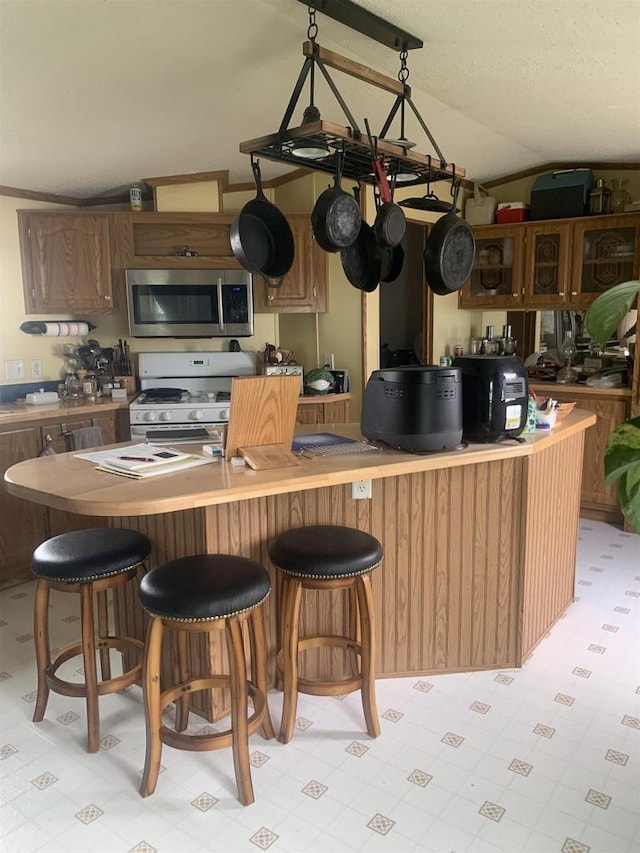 39 Douglas St, Westby, WI 54667 - kitchen featuring stainless steel microwave, white range with gas stovetop, light floors, and a kitchen bar
