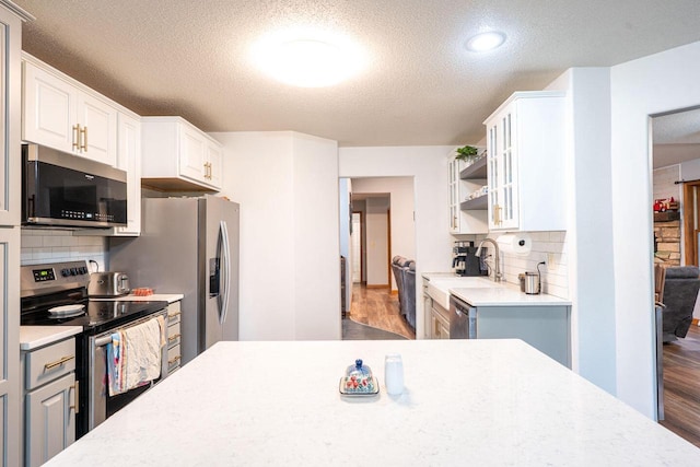 24301 Dexter Ave, Tomah, WI 54660 - kitchen featuring stainless steel appliances, a textured ceiling, light countertops, wood finished floors, and decorative backsplash