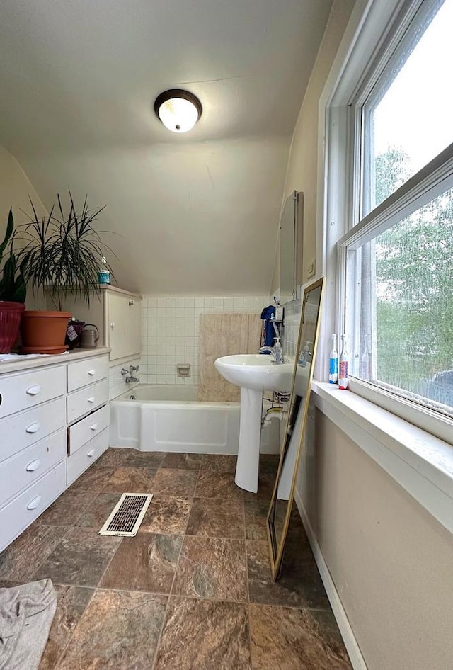 1340 Liberty St, Oshkosh, WI 54901 - bathroom featuring a bath, stone finish flooring, and lofted ceiling