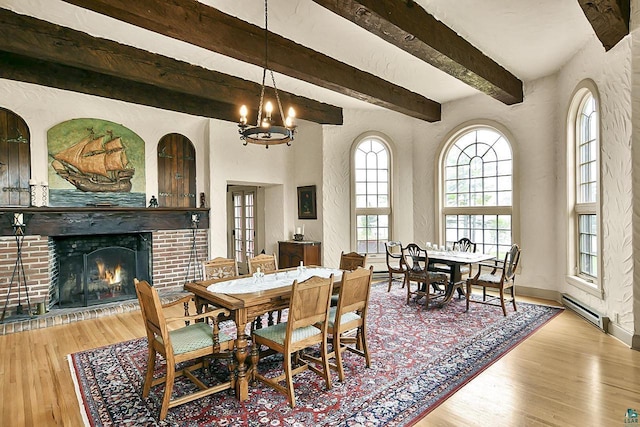 933 Nebraska Row, La Pointe, WI 54850 - dining space featuring baseboard heating, wood finished floors, a brick fireplace, beam ceiling, and a chandelier