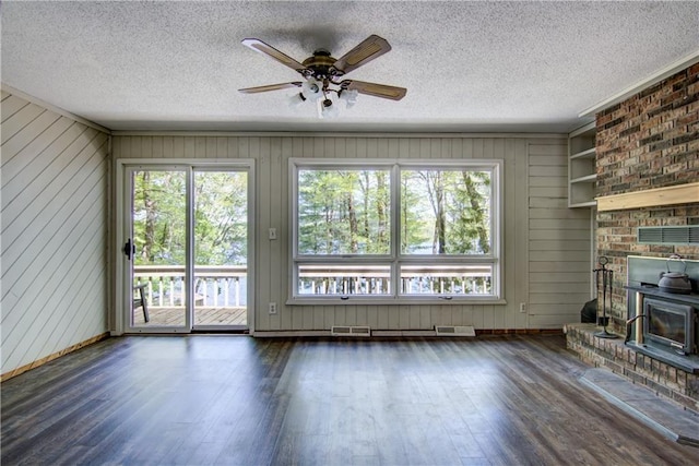 12272 Ewig Rd, Hayward, WI 54843 - unfurnished living room with a wood stove, plenty of natural light, wood finished floors, and a textured ceiling