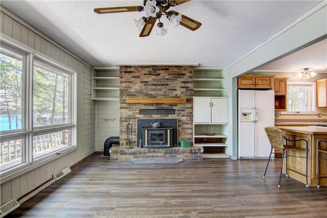 12272 Ewig Rd, Hayward, WI 54843 - living room with a textured ceiling, dark wood finished floors, a ceiling fan, a fireplace, and wood walls