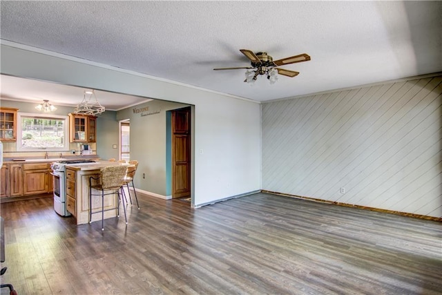 12272 Ewig Rd, Hayward, WI 54843 - kitchen featuring white gas stove, a breakfast bar area, light countertops, baseboards, and dark wood-type flooring