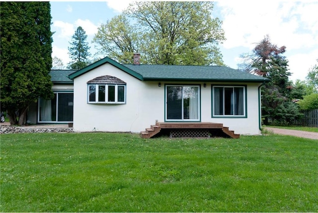 915 W Knapp St, Rice Lake, WI 54868 - rear view of house with a lawn, a chimney, stucco siding, entry steps, and roof with shingles