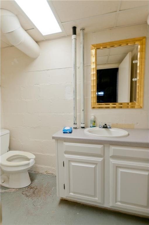 915 W Knapp St, Rice Lake, WI 54868 - bathroom with toilet, vanity, concrete block wall, and concrete floors