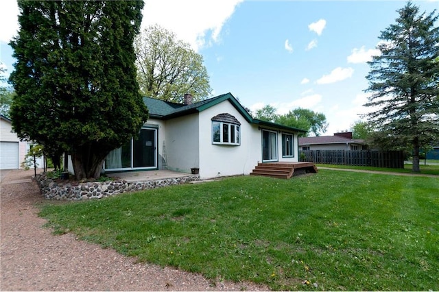 915 W Knapp St, Rice Lake, WI 54868 - rear view of house with stucco siding, a garage, and a chimney