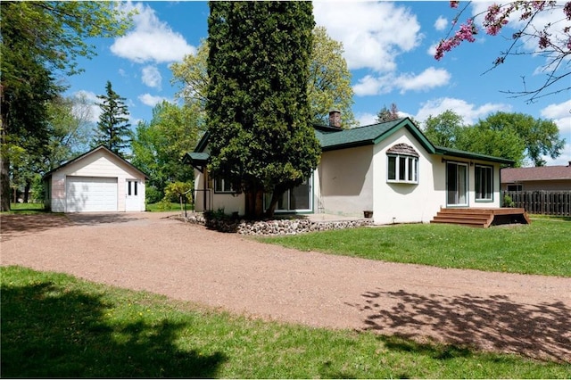 915 W Knapp St, Rice Lake, WI 54868 - view of front facade featuring dirt driveway, an outbuilding, a garage, a front yard, and stucco siding