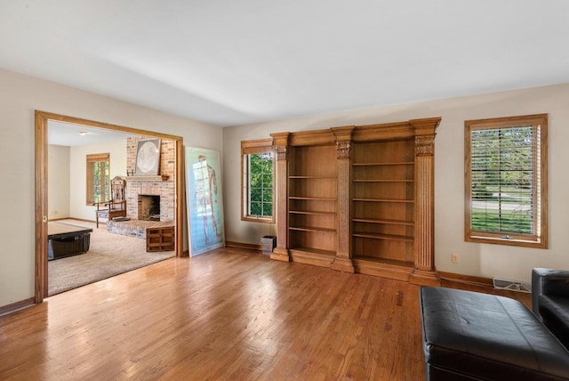 11616 N Lantern Ln, Mequon, WI 53092 - unfurnished living room with baseboards, a brick fireplace, and wood finished floors