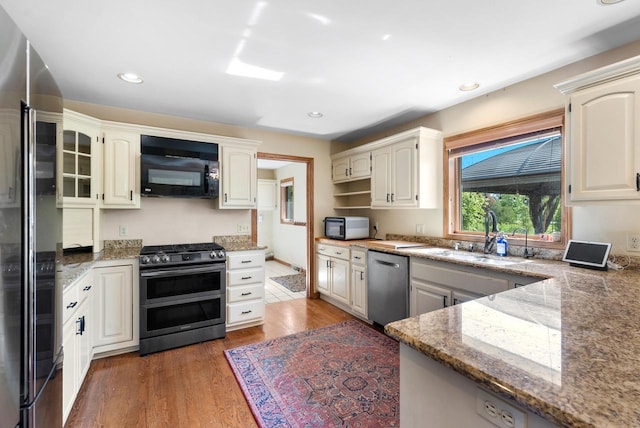 11616 N Lantern Ln, Mequon, WI 53092 - kitchen featuring appliances with stainless steel finishes, a sink, light stone countertops, light wood finished floors, and recessed lighting