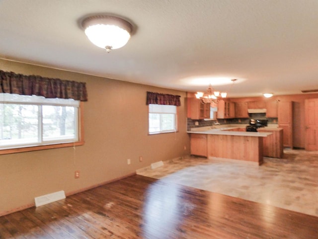 N11475 Post Lake Dr, Elcho, WI 54428 - kitchen featuring a chandelier, a peninsula, stove, light wood-style flooring, and exhaust hood