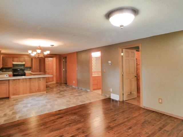 N11475 Post Lake Dr, Elcho, WI 54428 - kitchen with light wood finished floors, light countertops, black range with electric stovetop, a chandelier, and under cabinet range hood