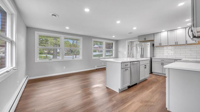 1007 Forest Hill Dr, Green Bay, WI 54311 - kitchen featuring stainless steel dishwasher, baseboard heating, decorative backsplash, an island with sink, and recessed lighting