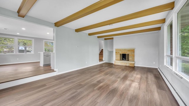1007 Forest Hill Dr, Green Bay, WI 54311 - unfurnished living room with beam ceiling, baseboard heating, wood finished floors, baseboards, and stairway