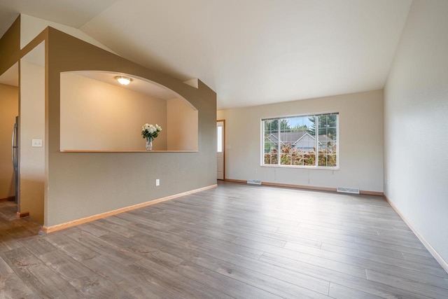 5406 Rock Rapids Dr, Weston, WI 54476 - unfurnished room featuring vaulted ceiling, wood finished floors, arched walkways, and baseboards