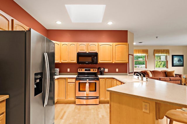 115 E Broadway Unit 210, Monona, WI 53716 - kitchen featuring stainless steel appliances, a sink, a peninsula, light brown cabinets, and a kitchen bar