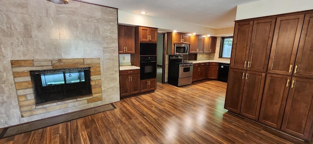3315 N 12th St, Wausau, WI 54403 - kitchen featuring black appliances, dark wood-style floors, light countertops, a stone fireplace, and recessed lighting