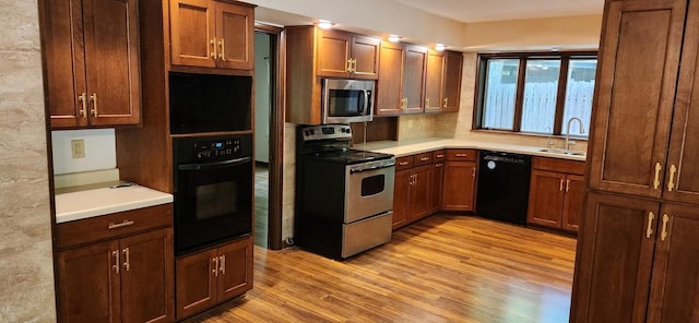3315 N 12th St, Wausau, WI 54403 - kitchen featuring black appliances, light wood-type flooring, a sink, and light countertops